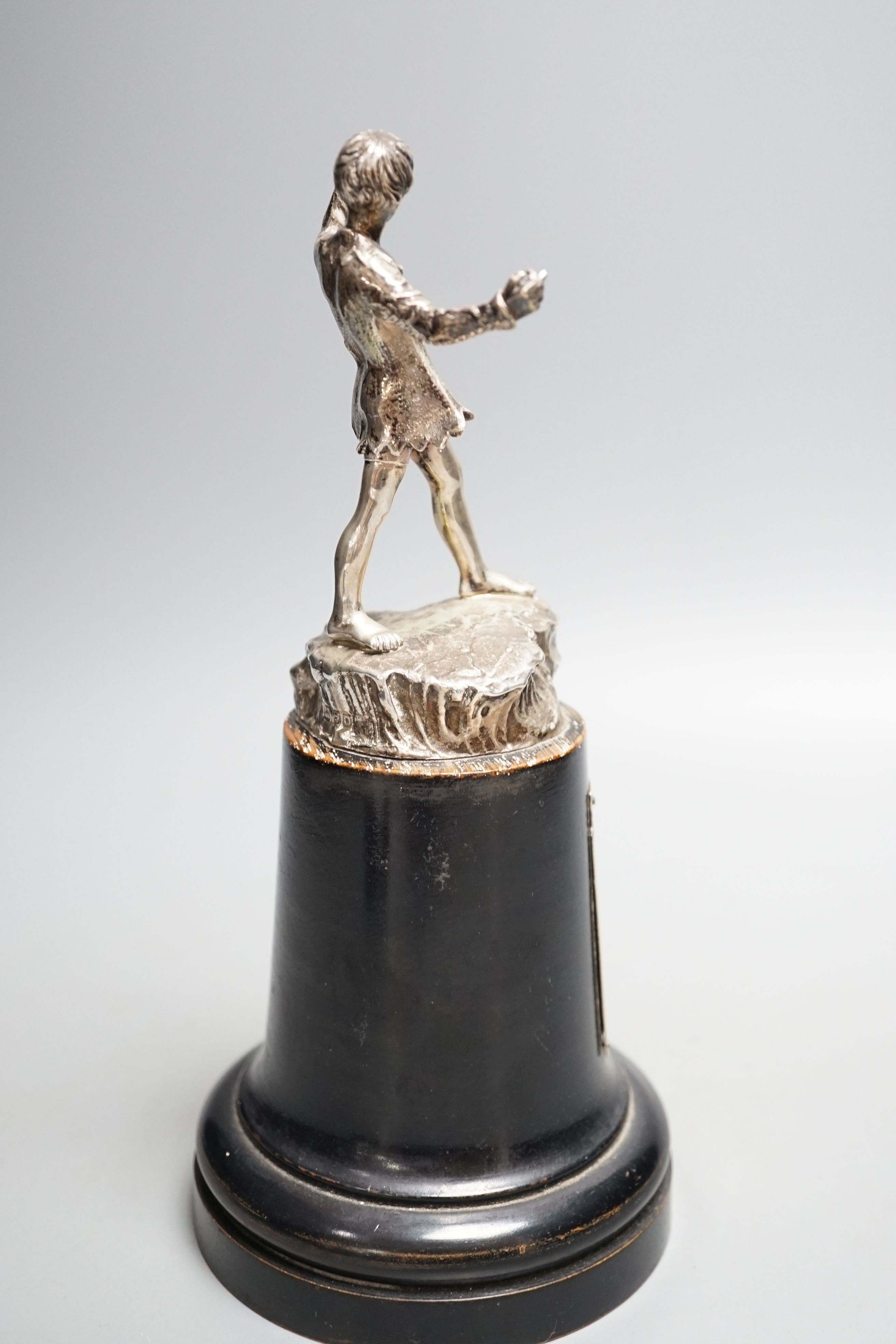 A late 1940's silver presentation figure of a young boy playing the pipes, on a rocky base, Goldsmiths & Silversmiths Co Ltd, London, 1949, on a wooden plinth with engraved presentation plaque, overall height 23.5cm